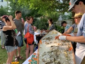 a group of people standing around a table filled with oysters