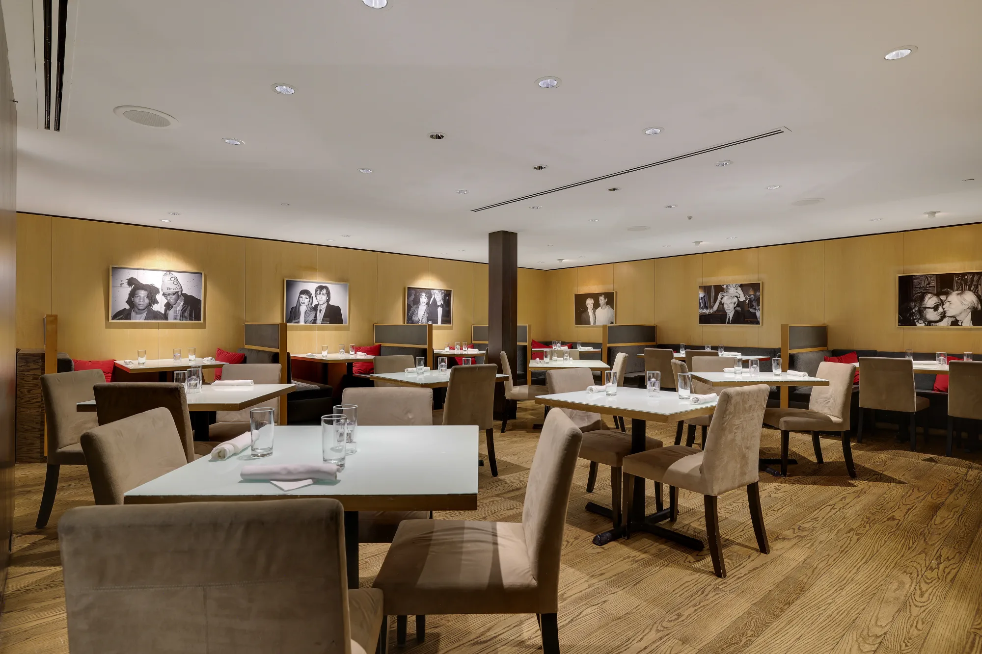 The Bar Louis dining room features modern square tables, upholstered chairs, and iconic black-and-white portraits.