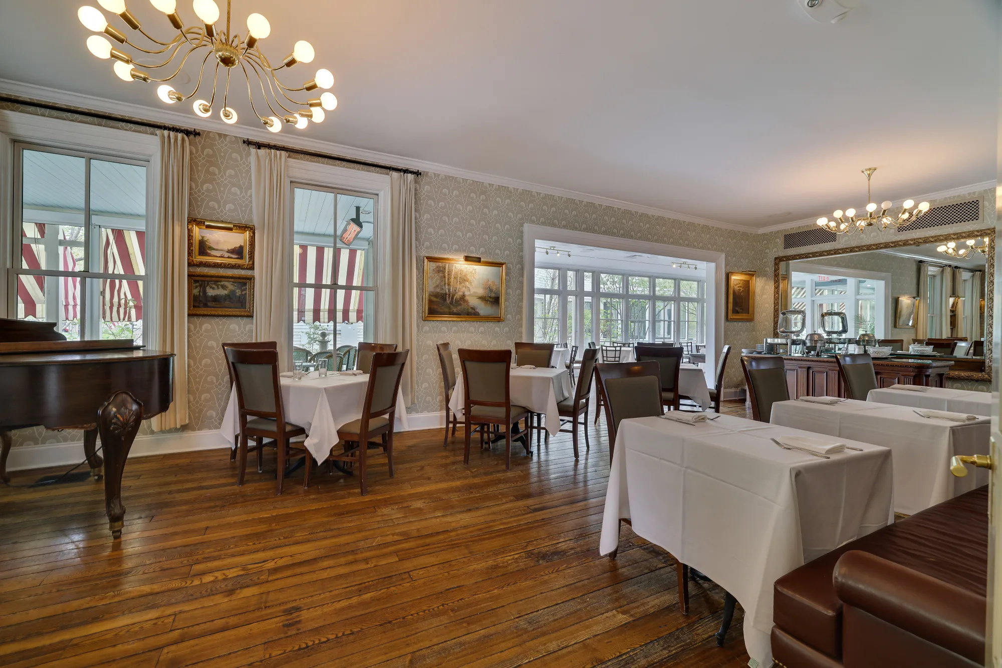 Set tables with white linens and a piano create a classic atmosphere for Milford PA dining in the Delmonico Room.