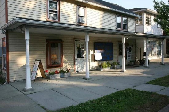 A cream-colored clapboard building with a covered porch in the Milford historic district under soft daylight.