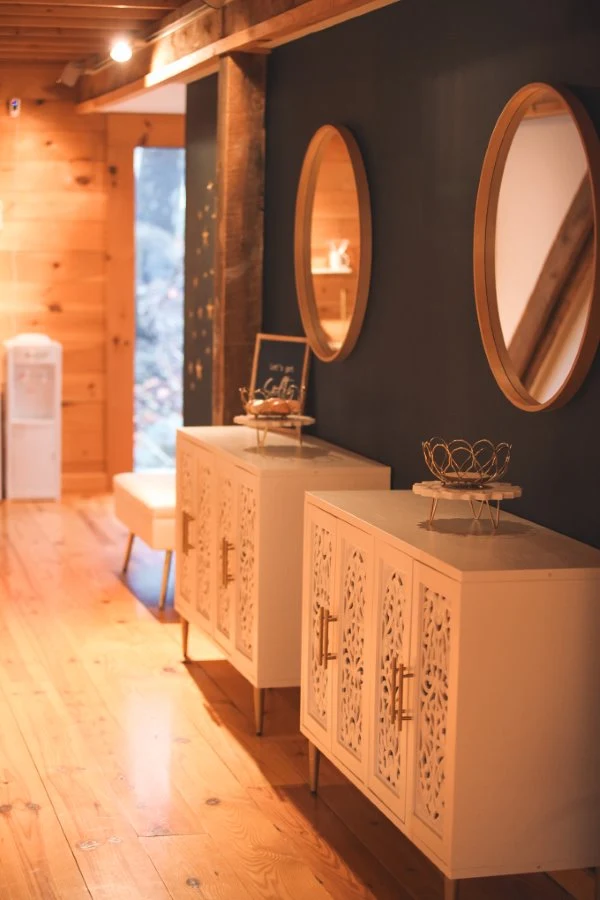 Intricately carved white cabinets and oval mirrors decorate a warm wood hallway at our Milford, PA accommodations.