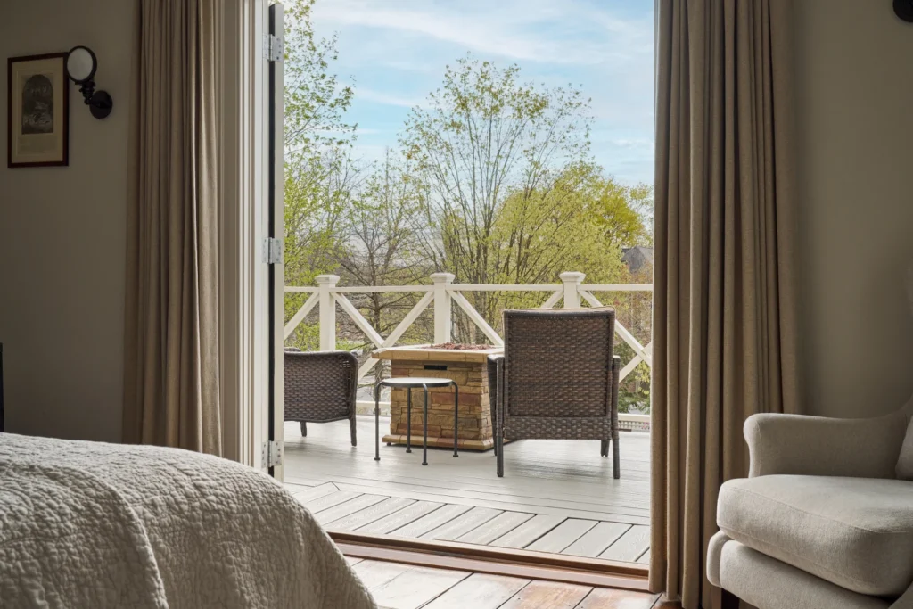 Wicker chairs and a fire pit table sit on a private balcony overlooking trees at a Milford, PA hotel.