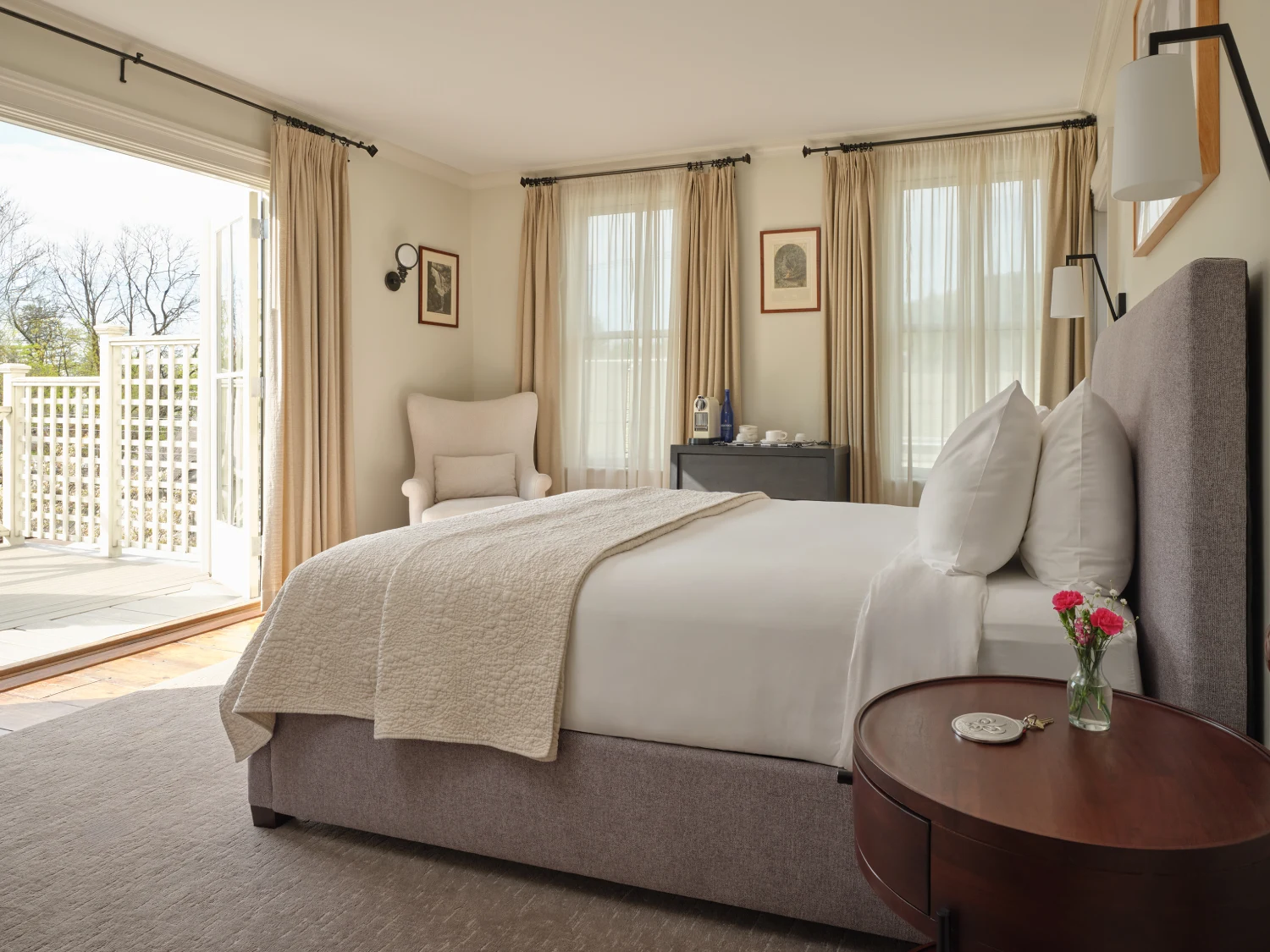 A bright, elegant guest room at Hotel Fauchère featuring a plush bed and open doors to a private sun-drenched balcony.