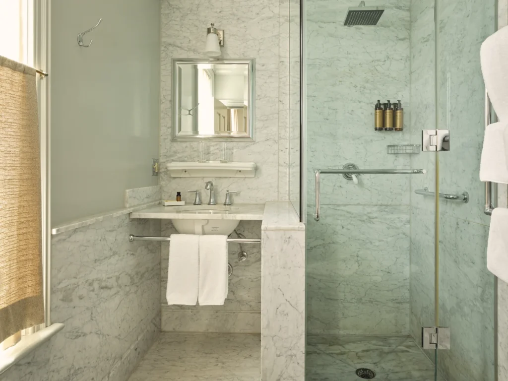A luxury marble bathroom featuring a walk-in glass shower and modern vanity at Hotel Fauchère in Milford, PA.