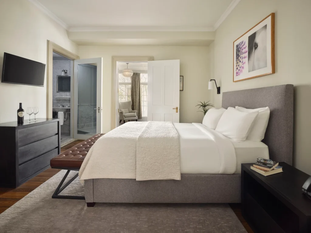 A bright guest room featuring a plush king bed and a view into a marble bathroom at Hotel Fauchère.