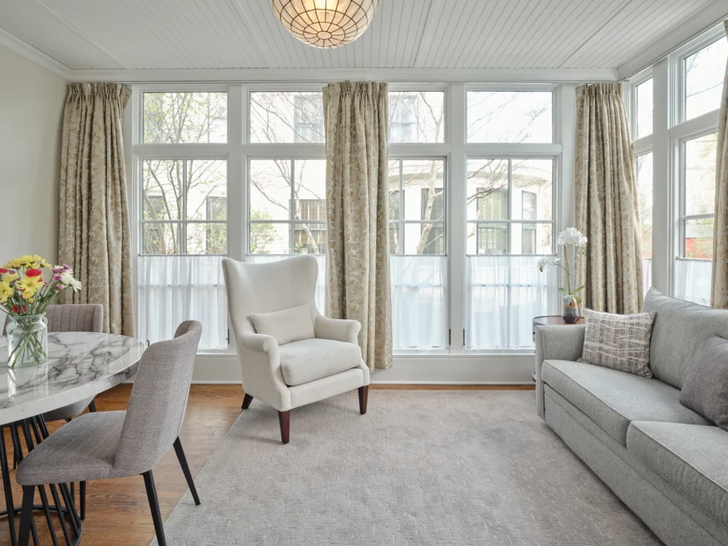 A bright sunroom at Hotel Fauchère with a wingback chair and sofa, offering premium Milford PA accommodations.