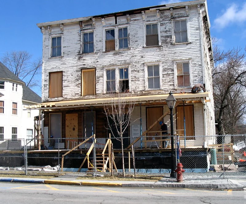 Construction crews work to restore a historic white building in the Milford historic district.