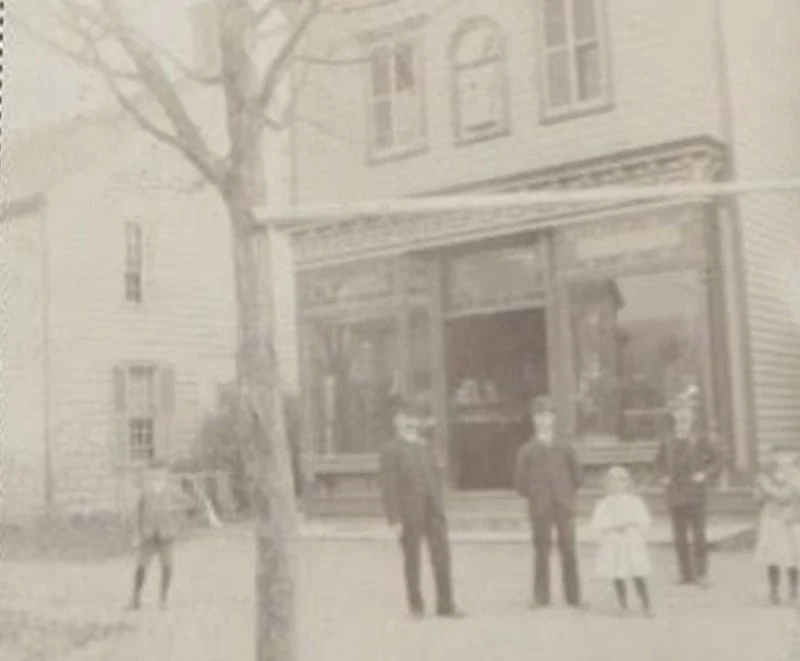 A vintage sepia photograph of residents outside a building in the Milford historic district.