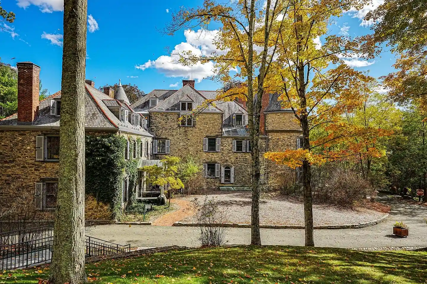 A historic stone building sits amidst golden autumn foliage in the Milford historic district.