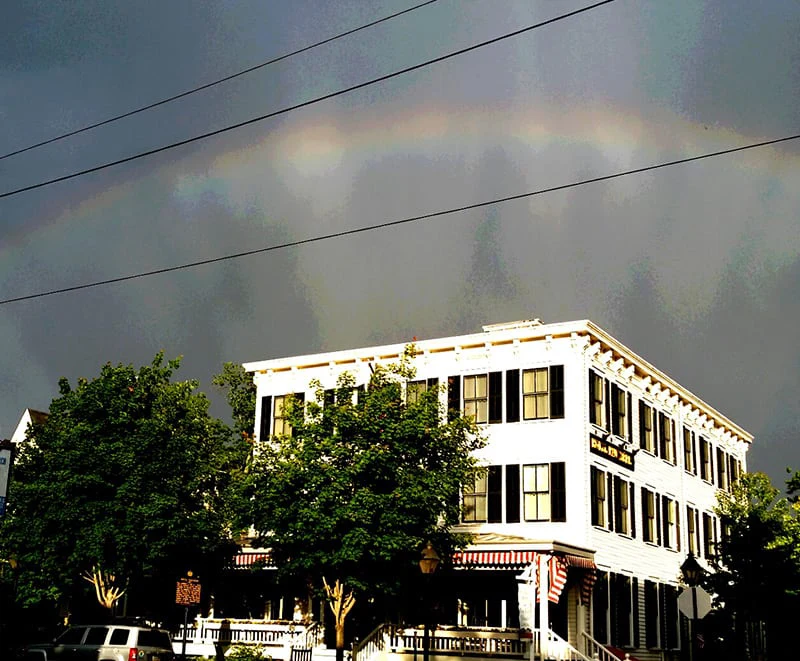 A rainbow appears above the white historic Hotel Fauchère building in the Milford historic district.