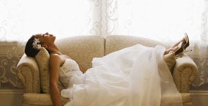 Woman laying on couch in a wedding dress