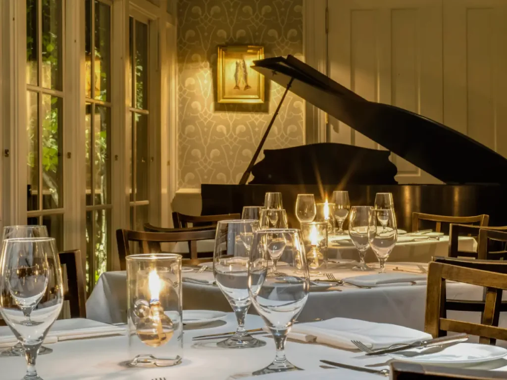 Elegant candlelit tables and a grand piano create a warm atmosphere for dining in Milford, PA.
