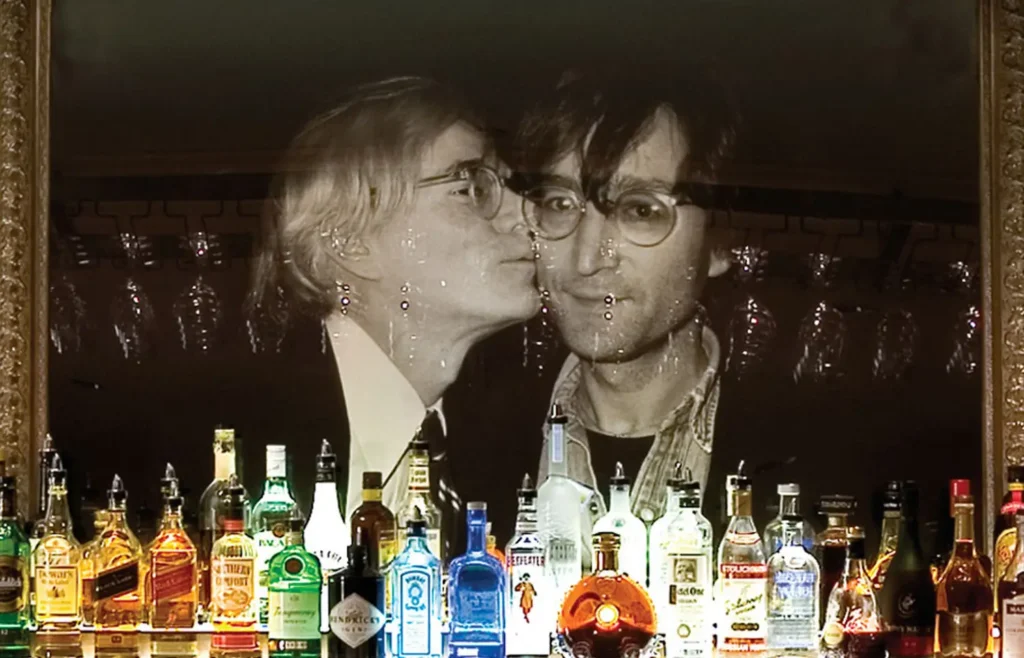 A row of liquor bottles sits before a famous portrait of Andy Warhol and John Lennon at Bar Louis in Milford, PA.